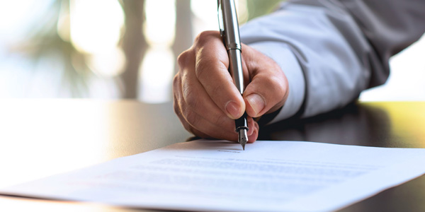 A Corporate Businessman Signing His Written Permission To Conduct Background Checks.